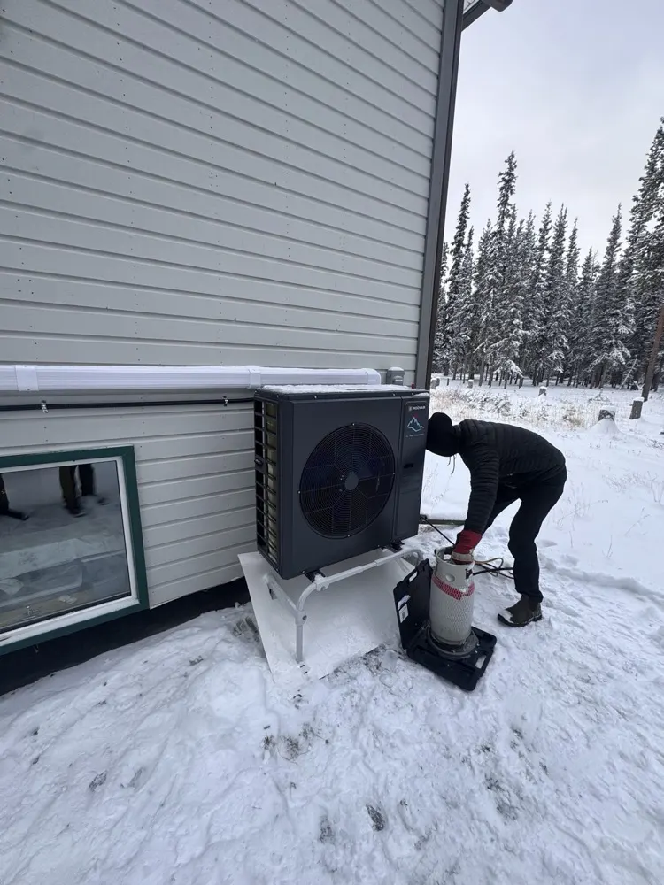 All Yukon Refrigeration technician installing a heat pump in the snow